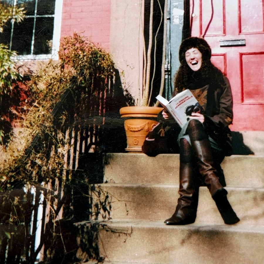 Melanie Challenger reading The Singing Neanderthals on a doorstep.