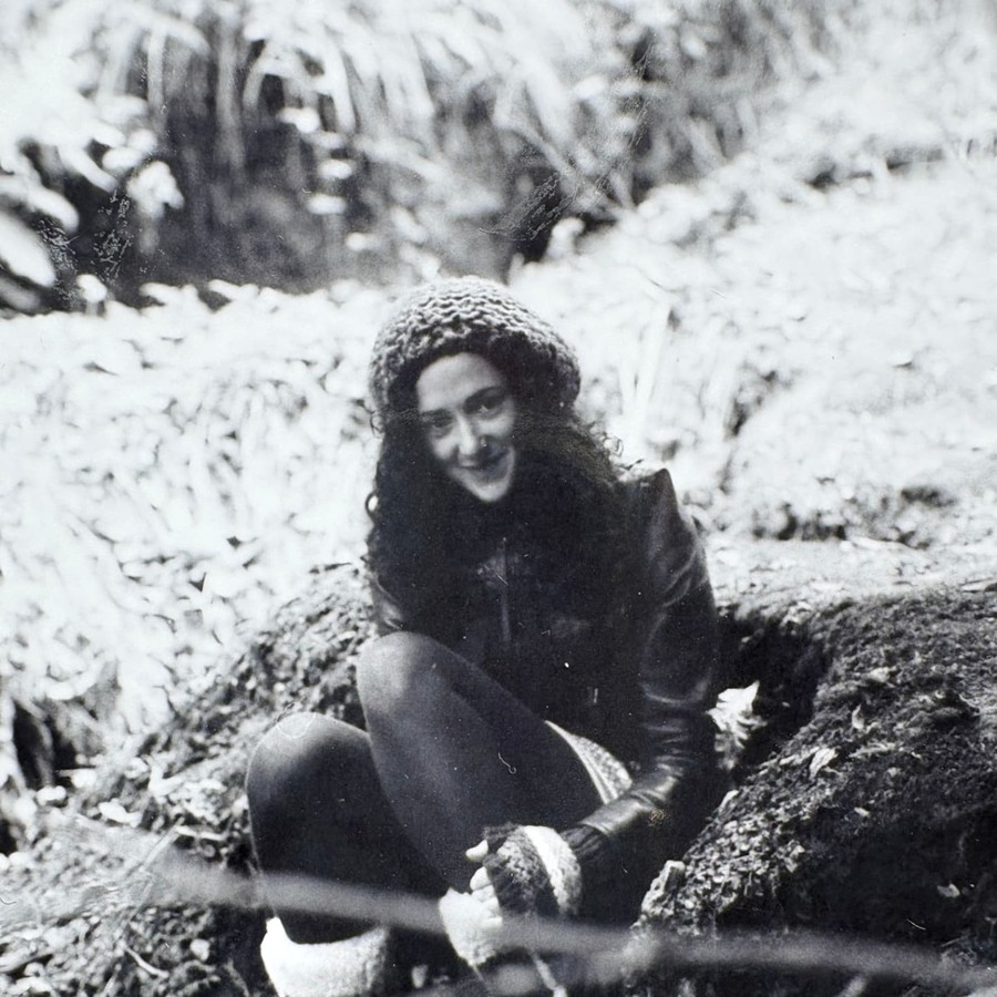 Melanie Challenger sitting on mossy ground in winter woodland.